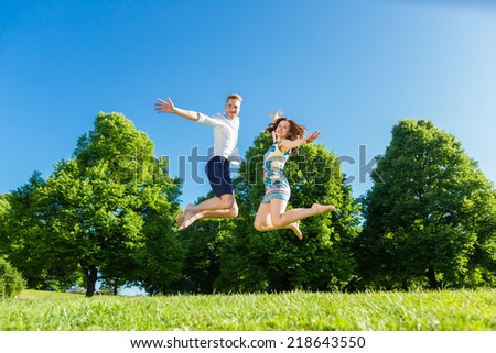 Couple in love jumping on park lawn