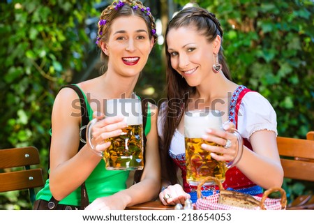 In Beer garden Ã?Â¢?? female friends in Tracht, Dirndl and Lederhosen drinking a fresh beer in Bavaria, Germany