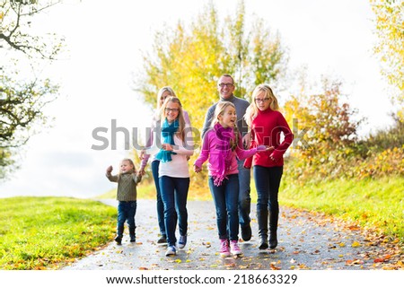 Girls going ahead at family walk through the park in fall or autumn