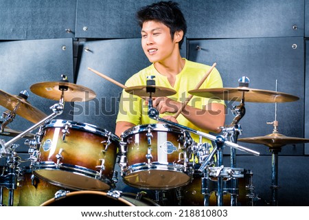 Asian professional musician drummer playing drums in recording studio