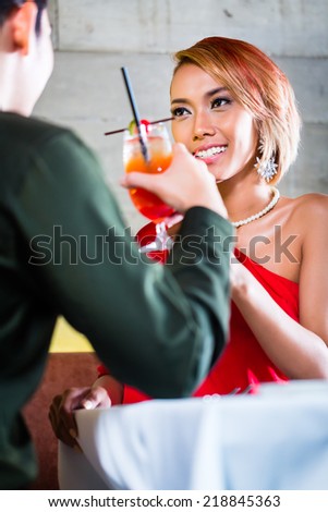 Asian couple drinking cocktails in fancy bar