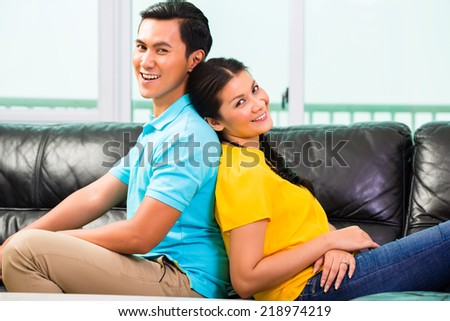 Young Asian handsome couple having long-term relationship sitting on sofa or couch