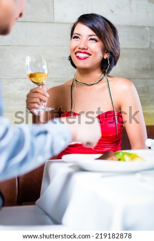 Asian couple having dinner and drinking red wine in very fancy bar or restaurant