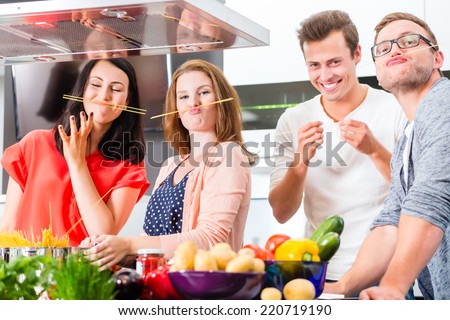 Friends cooking spaghetti and meat in domestic kitchen