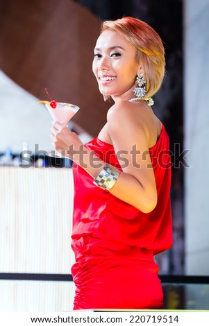 Asian woman drinking cocktails in fancy bar or club