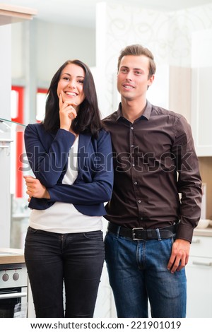 Man and woman buying domestic kitchen in studio or furniture store