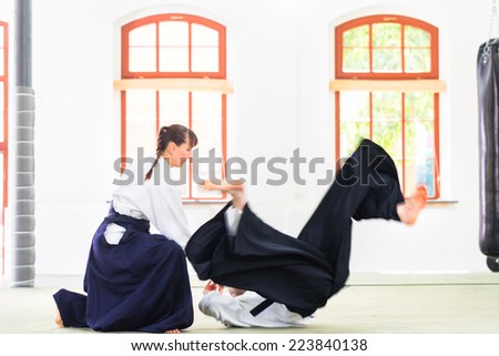 Man and woman fighting at Aikido training in martial arts school