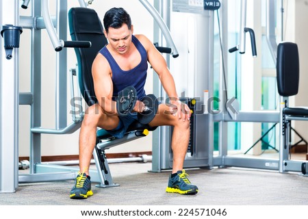 Asian man lifting hand weight at gym