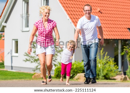 Family of Parents and child walking in front of home in village or suburb