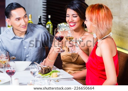 Asian friends, two couples, dining in fancy restaurant eating good food and drinking wine