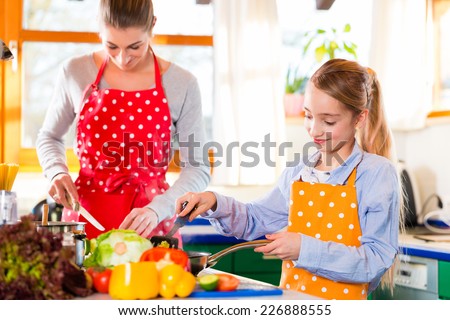 Mother showing daughter how to cook in domestic kitchen