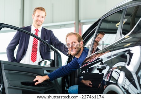 Seller or car salesman and client or customer in car dealership presenting the interior decoration of new and used cars in the showroom