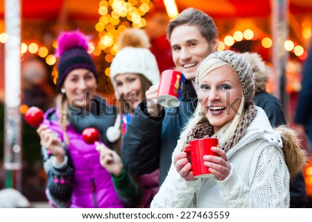 Friends drinking mulled wine and eating crystalized appkes on German Christmas Market