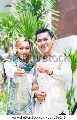 Asian Muslim man and woman moving into house presenting latchkey or key
