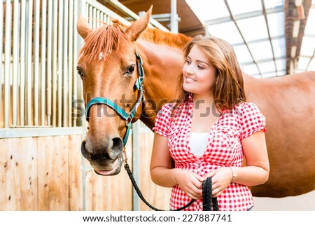 Woman leading pony in horse stable