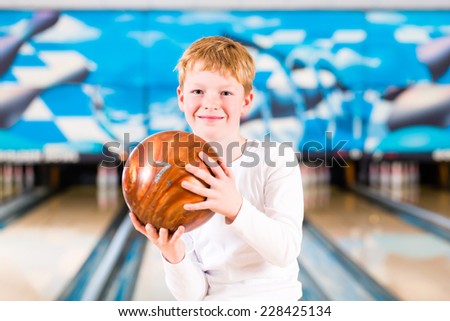 Child bowling with ball in alley