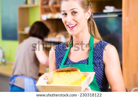 Saleswoman at organic supermarket counter offering cheese