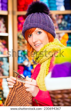 Young woman or saleswoman in knitting shop showing or explaining how to knit with circular needle
