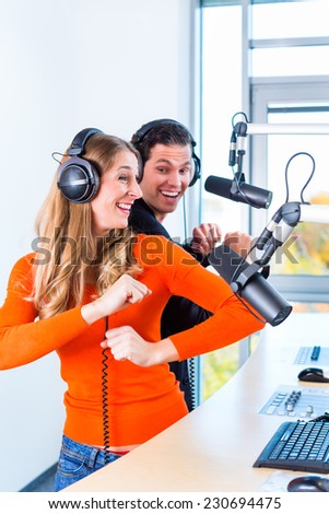 Presenters or moderators - man and woman - in radio station hosting show for radio live in Studio