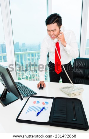 Asian businessman  on phone working in office