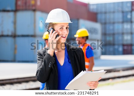 Manager with phone talking on shipment yard in front of container