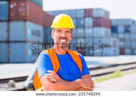 Worker standing in front of row of containers on port or yard of shipment company