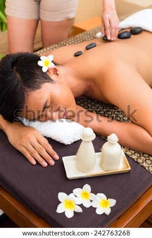 Indonesian Asian man in wellness beauty day spa having hot stone massage or treatment, looking relaxed