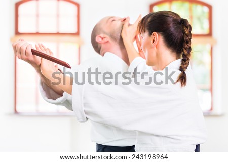 Man and woman fighting with wooden knifes at Aikido training in martial arts school