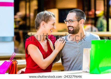 Man and woman in shopping mall with bags resting