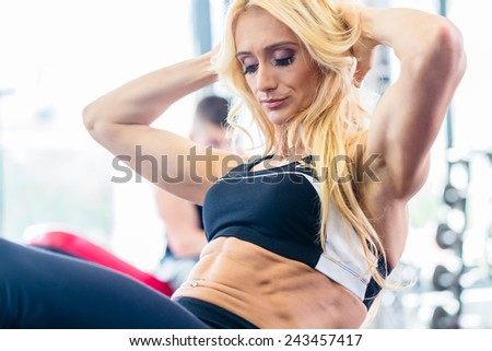 Bodybuilding woman doing sit-up in fitness gym for flat stomach