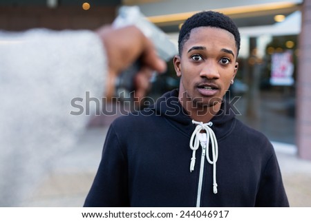 Young black man being threatened with gun in the street by a robber or gang