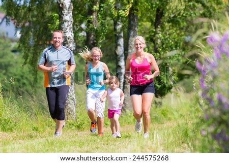 Parents with children sport running together through forest