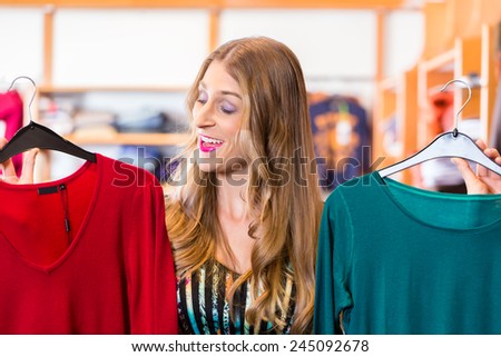 Woman choosing clothes on clothes rail in boutique or fashion store
