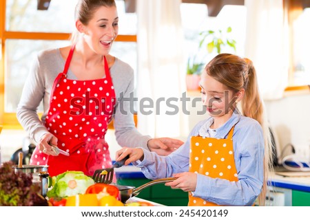 Mother showing daughter how to cook in domestic kitchen