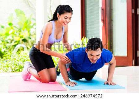 Asian woman helping man with push-up to gain better fitness