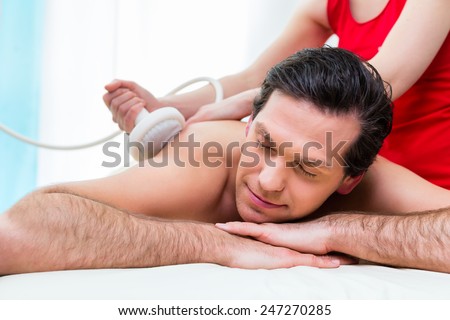 Man having relaxing herbal bag back massage in wellness spa