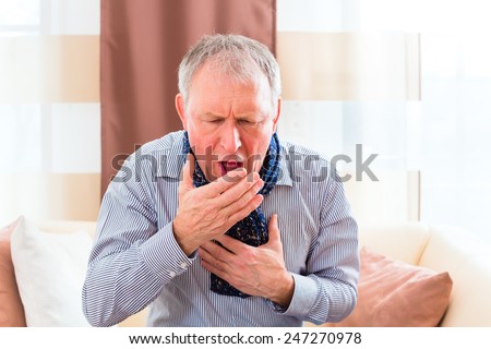 Old man coughing and holding breast having a bad cold