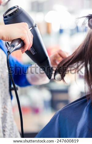 Female coiffeur blow dry women hair with blow dryer in shop