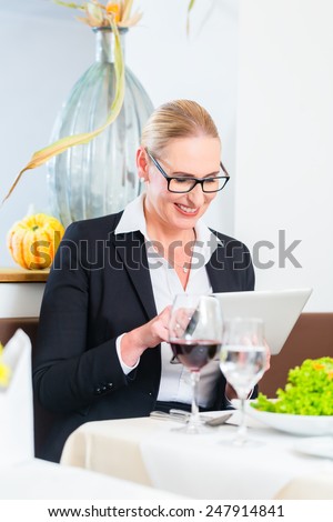 Business woman with tablet in restaurant having lunch in restaurant