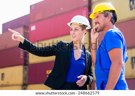 Freight shipping at container terminal of port, worker and manager discussing shipments