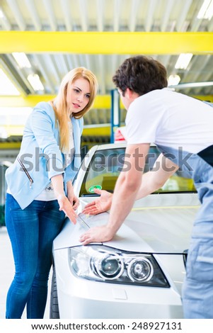 Male mechanic examine car finish on dents or scratches in workshop