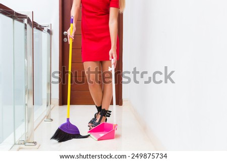 Woman or housewife cleaning up sweep floor with hand broom and shovel
