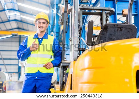 Forklift driver standing proud in manufacturing plant Forklift driver standing proud in manufacturing plant