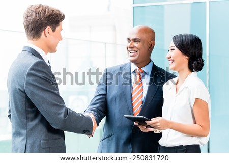 Indian CEO and Caucasian executive having business handshake in front of city skyline