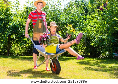 Couple in garden with watering can and barrow