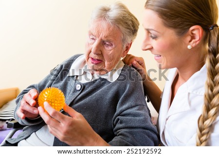 Nurse giving physical therapy with massage ball to senior woman in wheelchair