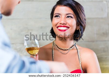 Asian couple having dinner and drinking red wine in very fancy bar or restaurant