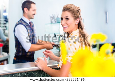 Woman customer ordering espresso or cappuccino at bar counter in coffee shop