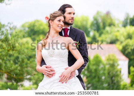 Wedding bride and groom outside in the garden, groom embracing bride