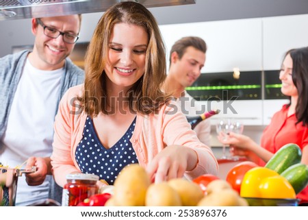 Friends cooking pasta and meat in domestic kitchen